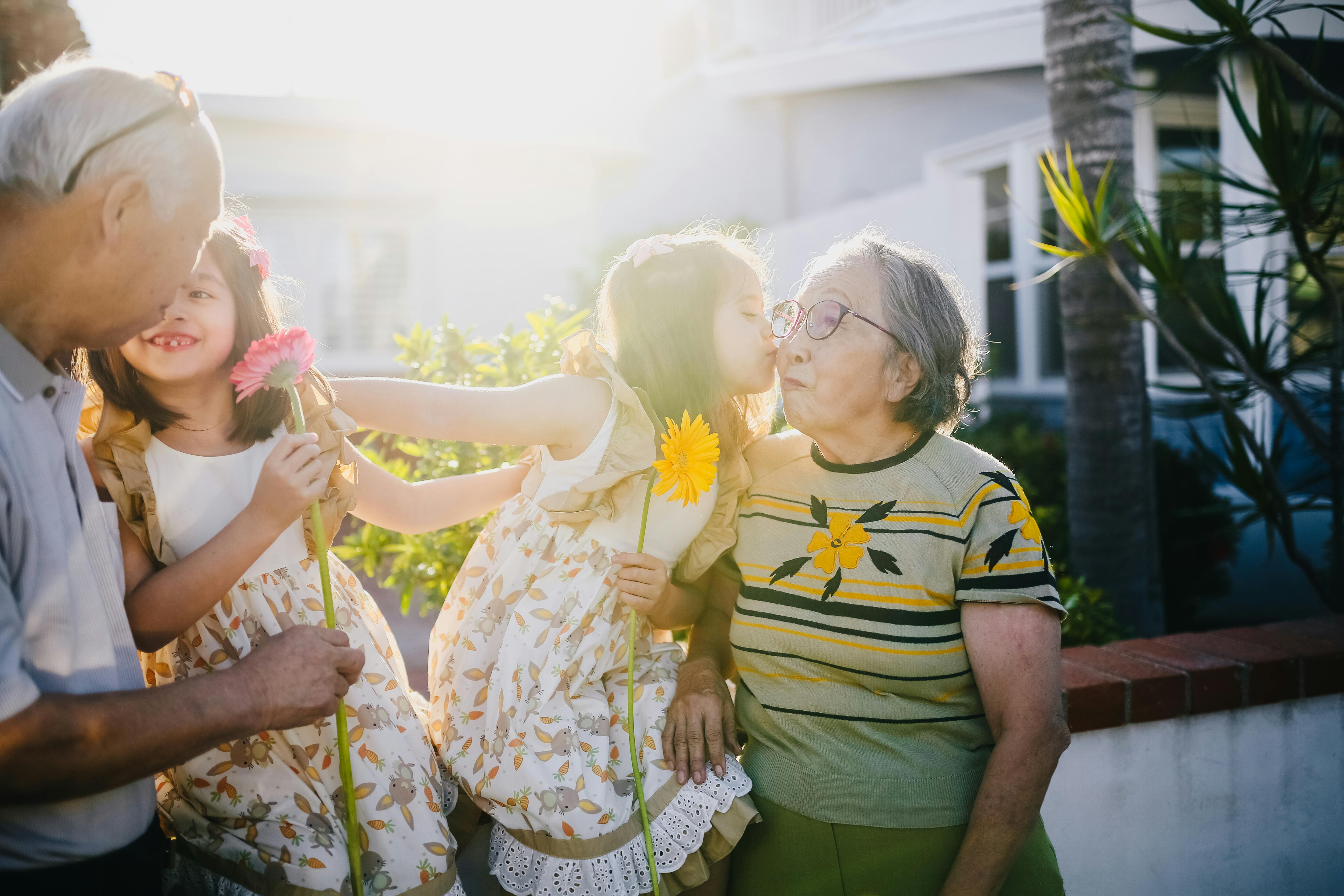 A grandmother, grandfather and their two granddaughters sharing a warm moment outdoors